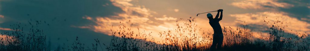long wide image - golfer hitting a ball in the sunset