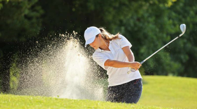 female golfer using irons in a sand trap