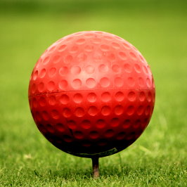 red colored golf ball on a tee
