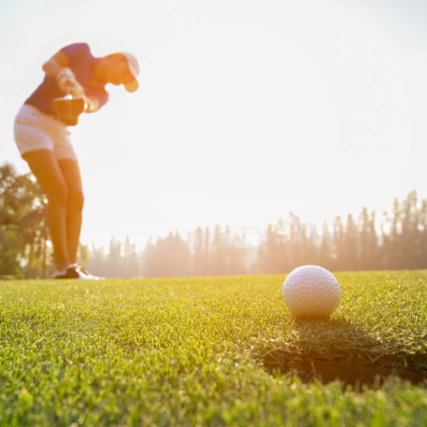 women making a golf shots sinking the ball into the hole