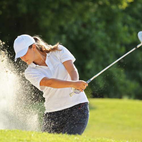 iron set - female golfer using irons in a sand trap